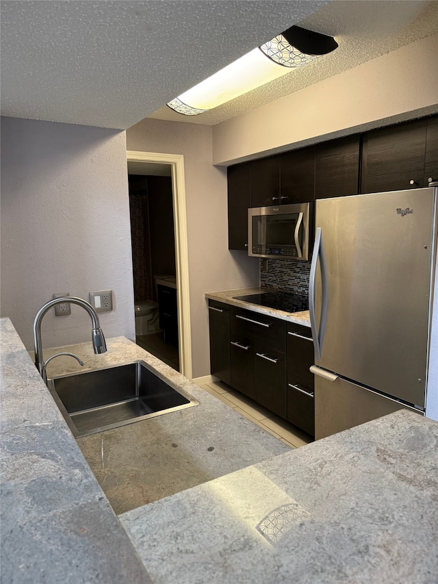 kitchen with light tile patterned flooring, sink, dark brown cabinets, stainless steel appliances, and decorative backsplash