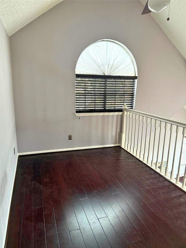 unfurnished room featuring lofted ceiling, ceiling fan, dark wood-type flooring, and a textured ceiling