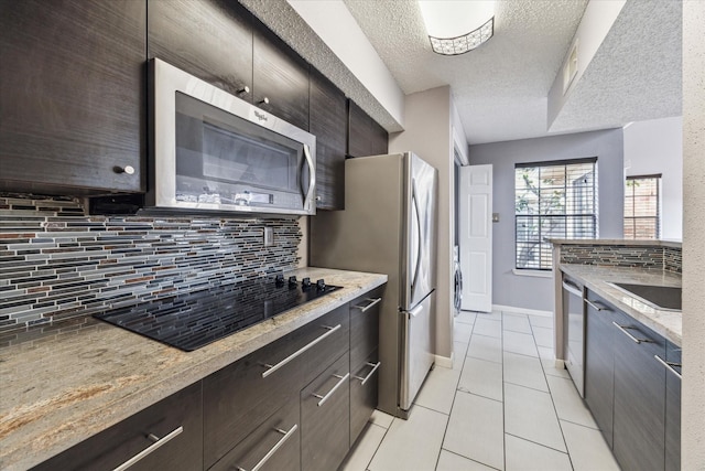 kitchen with sink, tasteful backsplash, light tile patterned floors, stainless steel appliances, and light stone countertops