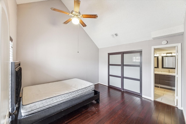 bedroom featuring lofted ceiling, ensuite bath, dark hardwood / wood-style flooring, a closet, and ceiling fan