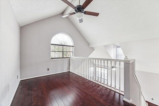 unfurnished room featuring hardwood / wood-style flooring, ceiling fan, lofted ceiling with beams, and a textured ceiling