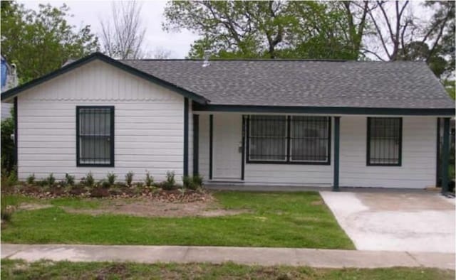 ranch-style home featuring a shingled roof and a front yard