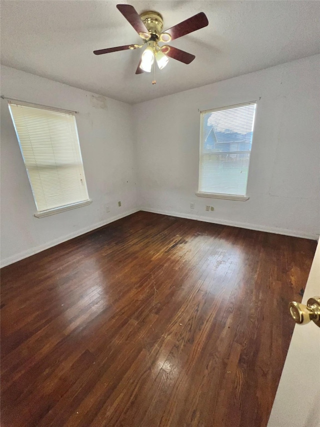 spare room with ceiling fan, dark wood-type flooring, and baseboards