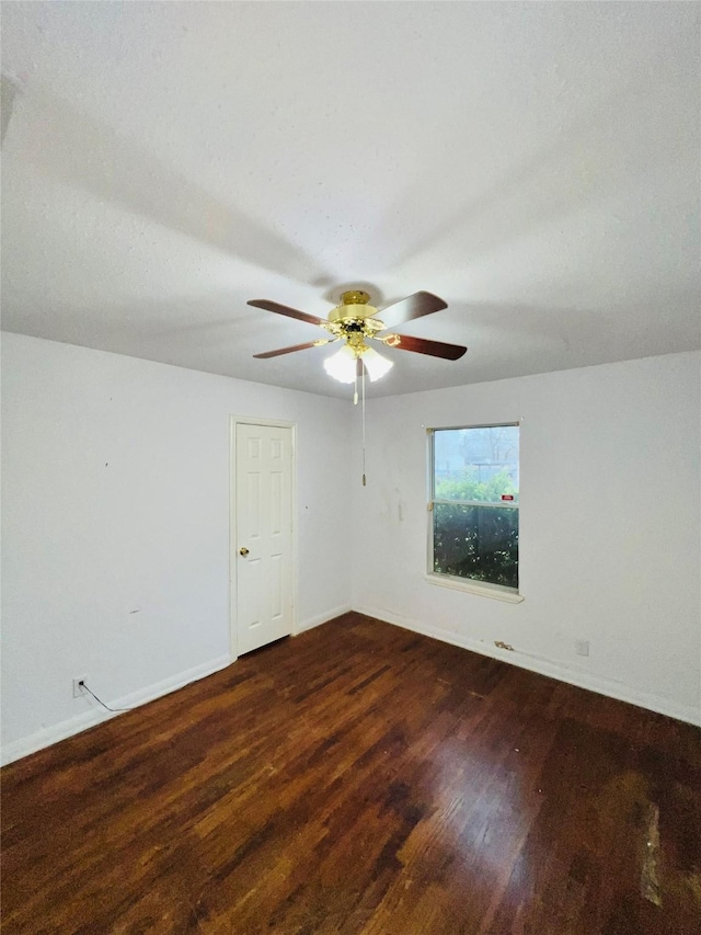 unfurnished room with dark wood-style floors, ceiling fan, and baseboards