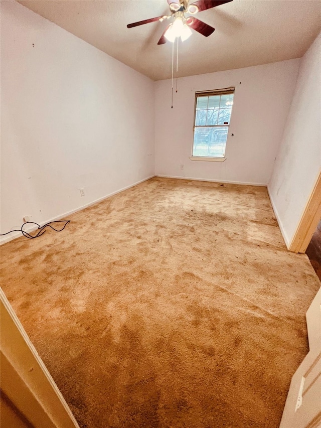 carpeted empty room featuring ceiling fan and baseboards