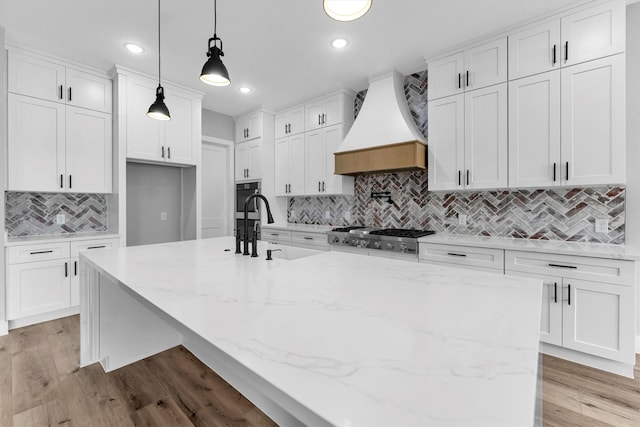 kitchen with white cabinetry, custom range hood, and pendant lighting