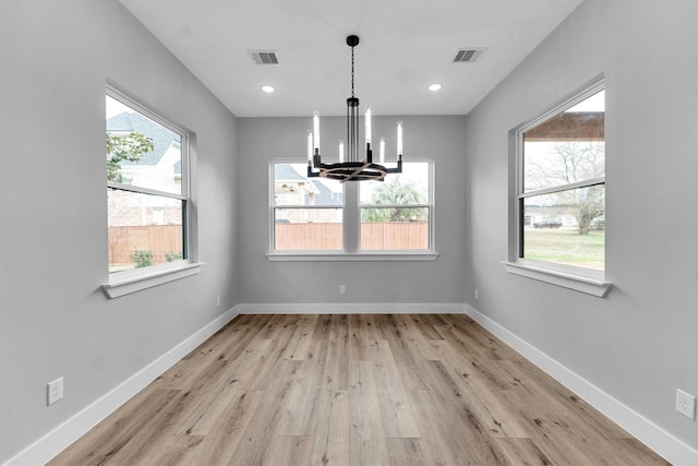 unfurnished dining area featuring light hardwood / wood-style flooring and a notable chandelier