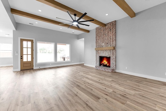 unfurnished living room featuring beamed ceiling, ceiling fan, a fireplace, and light hardwood / wood-style floors