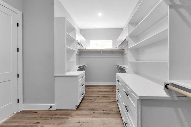 walk in closet with light hardwood / wood-style flooring