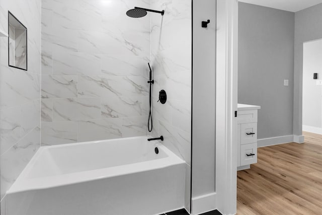 bathroom with tiled shower / bath combo, vanity, and wood-type flooring