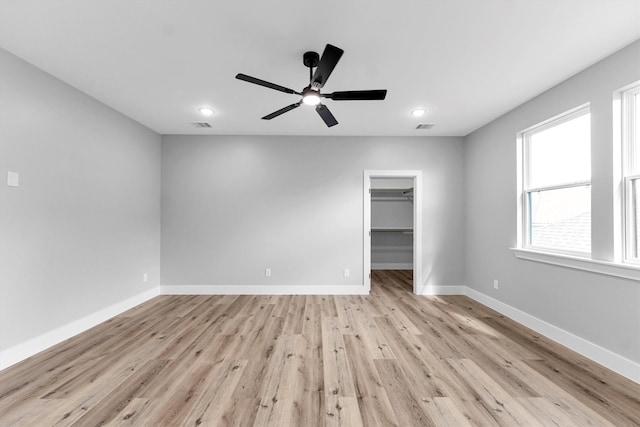 interior space with ceiling fan, a walk in closet, light hardwood / wood-style floors, and a closet