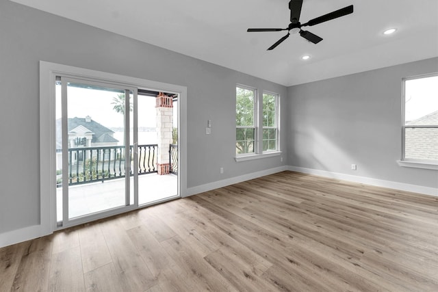 spare room featuring ceiling fan, vaulted ceiling, a healthy amount of sunlight, and light wood-type flooring