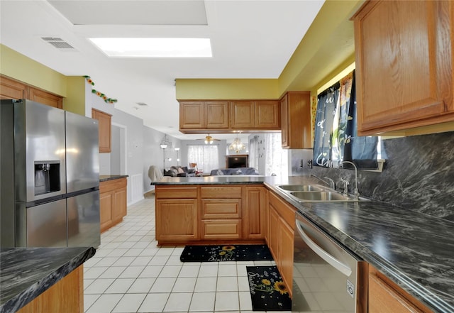 kitchen with appliances with stainless steel finishes, tasteful backsplash, sink, light tile patterned floors, and kitchen peninsula