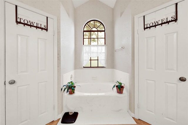 bathroom featuring lofted ceiling and a bathtub