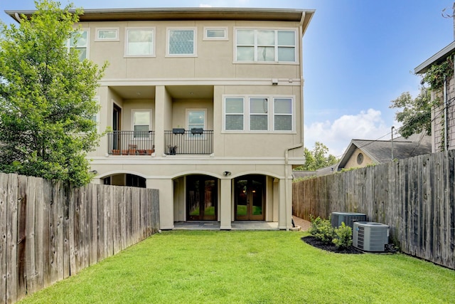 back of house featuring a balcony, a yard, cooling unit, and french doors