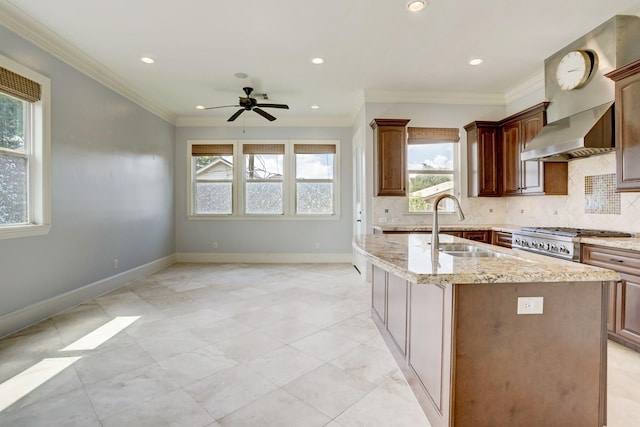 kitchen with a kitchen island with sink, sink, decorative backsplash, and light stone countertops