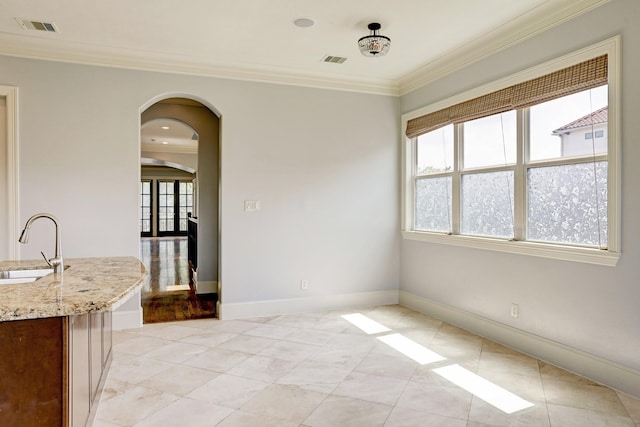 unfurnished dining area featuring light tile patterned floors, ornamental molding, sink, and a wealth of natural light