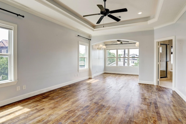 unfurnished room featuring hardwood / wood-style flooring, ceiling fan, crown molding, and a raised ceiling