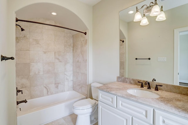 full bathroom featuring tiled shower / bath combo, vanity, tile patterned floors, toilet, and a chandelier