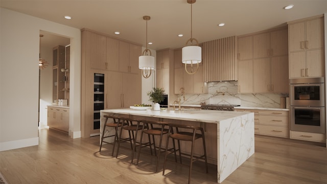 kitchen featuring appliances with stainless steel finishes, sink, an island with sink, and light brown cabinets