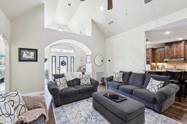 living room with ceiling fan, high vaulted ceiling, and light hardwood / wood-style floors