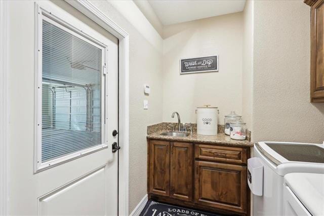 washroom with cabinets, washing machine and dryer, and sink