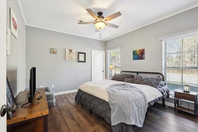 bedroom featuring dark hardwood / wood-style flooring, crown molding, and ceiling fan