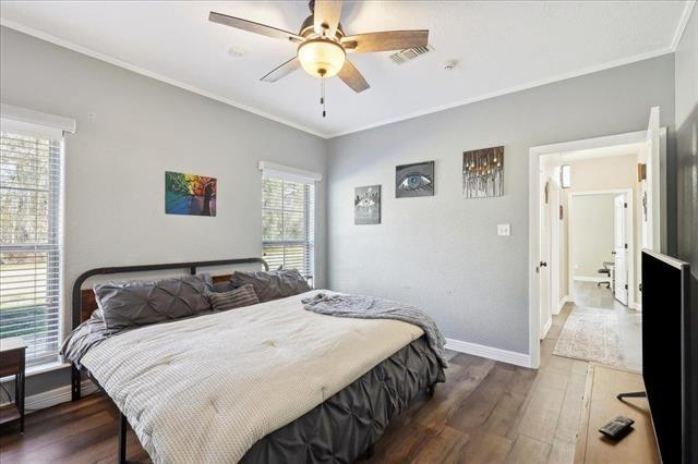 bedroom with dark hardwood / wood-style flooring, ornamental molding, and ceiling fan