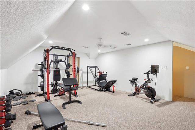 exercise room featuring vaulted ceiling and a textured ceiling