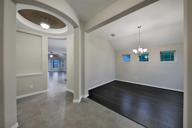 empty room with lofted ceiling, wood-type flooring, and an inviting chandelier