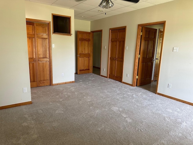 unfurnished bedroom featuring light colored carpet and a paneled ceiling