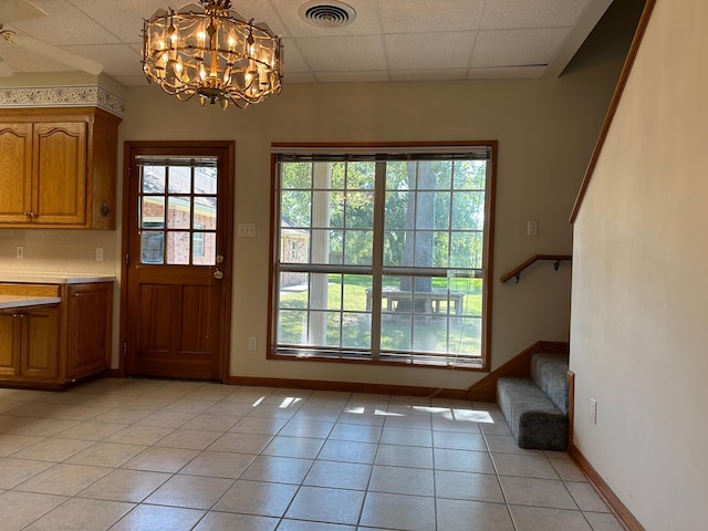 entryway with a wealth of natural light, a drop ceiling, and light tile patterned floors