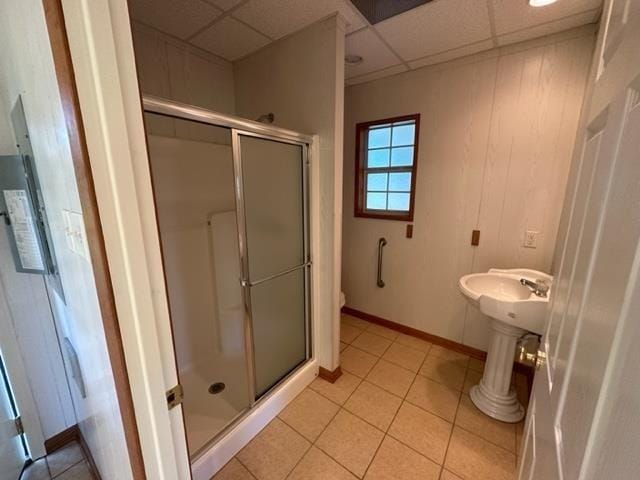 bathroom featuring tile patterned flooring, a paneled ceiling, a shower with door, and toilet