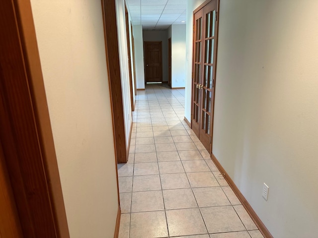 corridor featuring light tile patterned flooring and a paneled ceiling