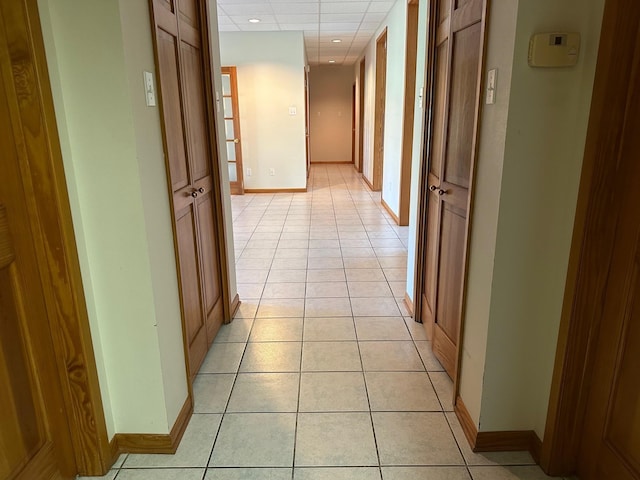 corridor with light tile patterned floors and a drop ceiling