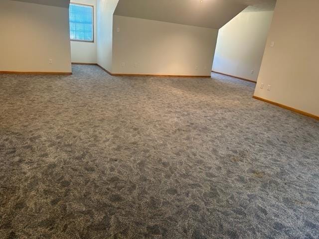 bonus room with vaulted ceiling and dark carpet