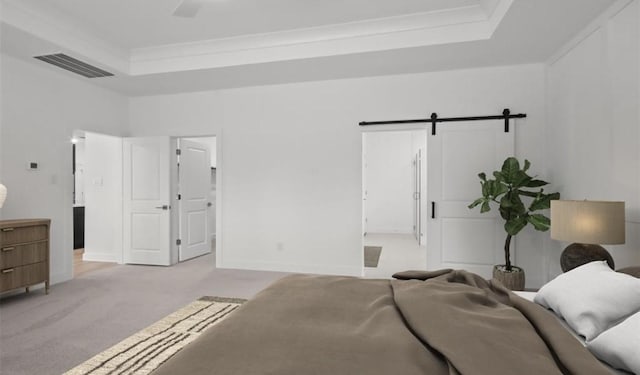 bedroom with a tray ceiling, a barn door, and light carpet