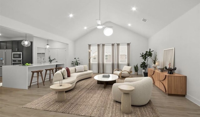 living room with sink, light hardwood / wood-style flooring, high vaulted ceiling, and ceiling fan