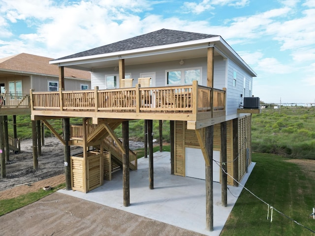 rear view of property with cooling unit, a garage, and a wooden deck