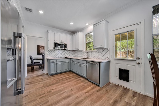 kitchen featuring sink, crown molding, backsplash, and appliances with stainless steel finishes