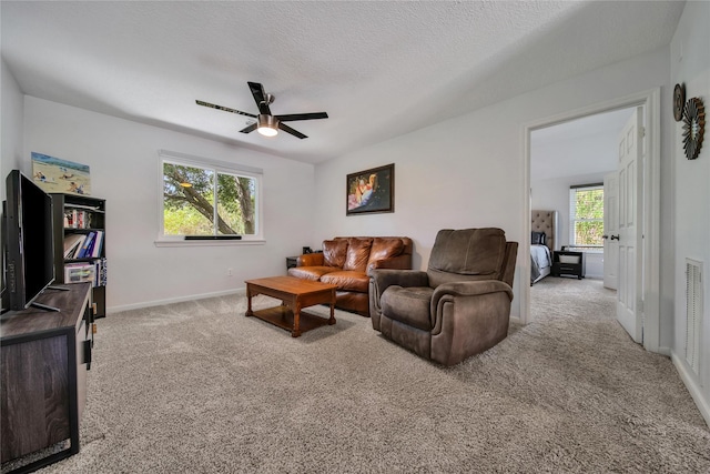 carpeted living room with ceiling fan and a textured ceiling