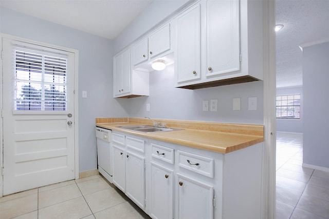 kitchen with light tile patterned flooring, sink, a textured ceiling, white dishwasher, and white cabinets