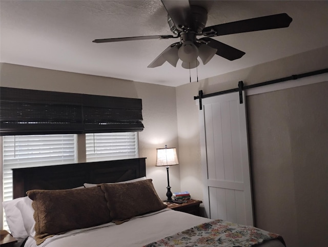 bedroom with ceiling fan and a barn door