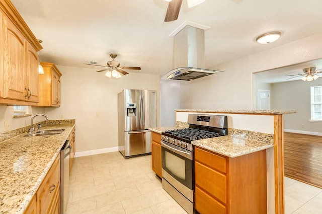 kitchen featuring island range hood, sink, ceiling fan, stainless steel appliances, and light stone countertops