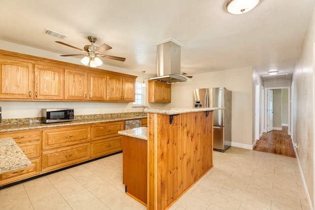 kitchen featuring a kitchen island, island exhaust hood, ceiling fan, stainless steel appliances, and light stone countertops