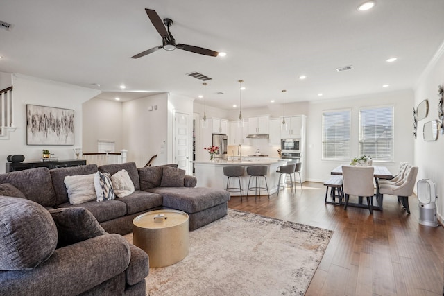 living room featuring dark hardwood / wood-style flooring, sink, crown molding, and ceiling fan