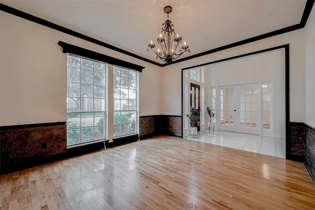 empty room featuring ornamental molding, light hardwood / wood-style flooring, and a notable chandelier