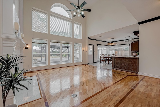 entryway with ceiling fan, light hardwood / wood-style floors, and a towering ceiling