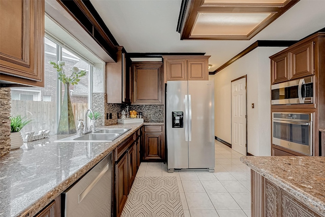 kitchen with light tile patterned flooring, appliances with stainless steel finishes, sink, decorative backsplash, and light stone counters