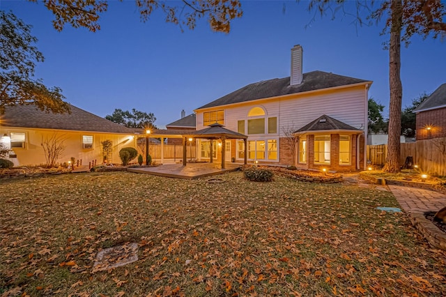 back house at dusk with a gazebo and a patio